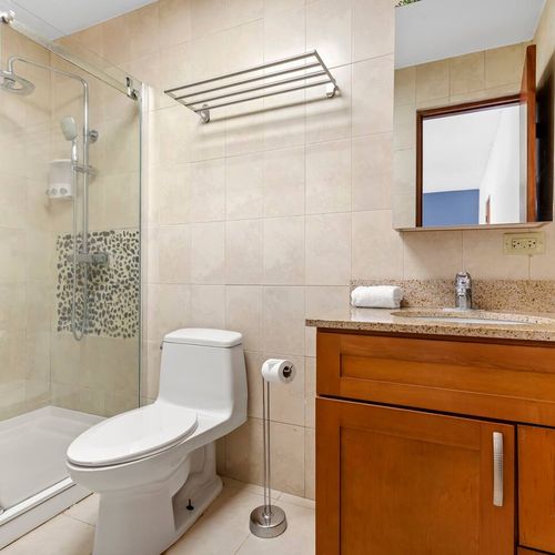 A chic and functional bathroom. The elegant wooden vanity and glass shower door combine style and practicality for a comfortable stay.