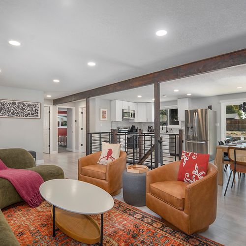 A vibrant main living room with bold colors and chic decor, seamlessly flowing into the open dining and kitchen areas for a spacious and welcoming feel.