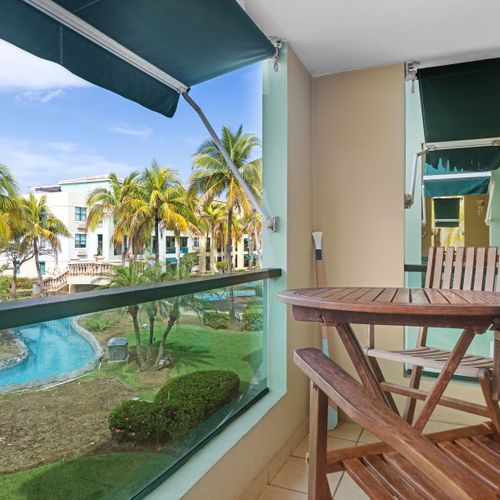 Relax in the shade of your covered balcony with a picturesque backdrop of the pool and palm trees.