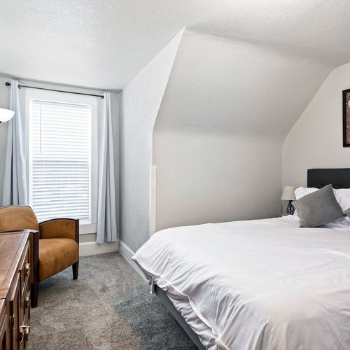 - comfortable bedroom with soft carpet, sloped ceiling, and clean design
- features a plush bed, cozy armchair, and elegant wood dresser with mirror
- peaceful ambiance ideal for rest, reading, or recharging between outings