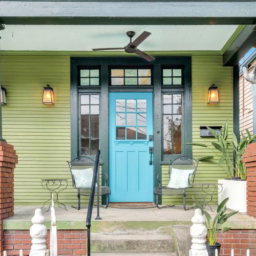 Welcoming front patio w/ seating tucked beneath a classic lantern.