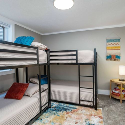 - functional bunk room perfect for kids or groups looking to share the space comfortably
- features two twin over twin metal bunk beds with cozy bedding & colorful throw pillows
- bright decor, wall art, & plush carpeting create a warm & welcoming vi