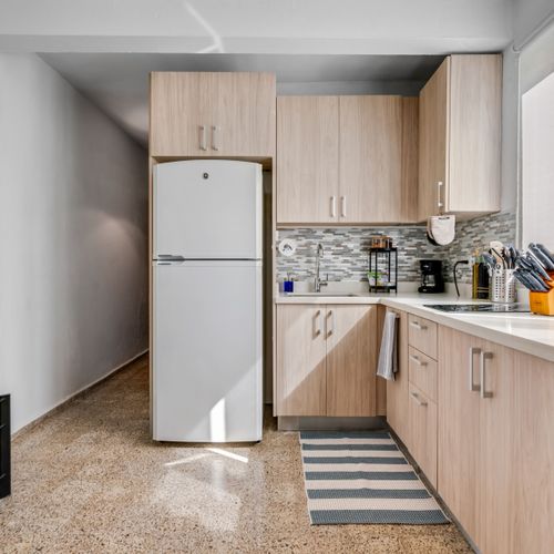 Fully Equipped Kitchen: Prepare your favorite meals in our bright and modern kitchen, featuring sleek wooden cabinetry, a full-sized refrigerator, and ample counter space for all your culinary adventures.