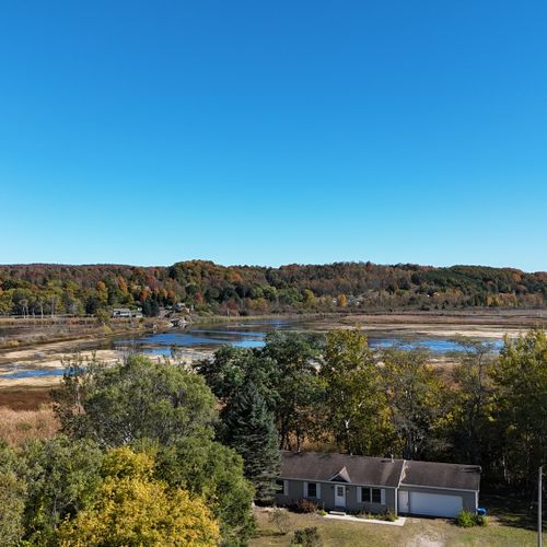 EXTERIOR:  Aerial photo of the home in late summer with the Betsie River in the background