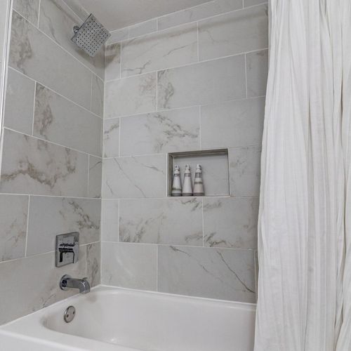 Tiled shower w/ sleek built-in niche — a refreshing start to any morning.