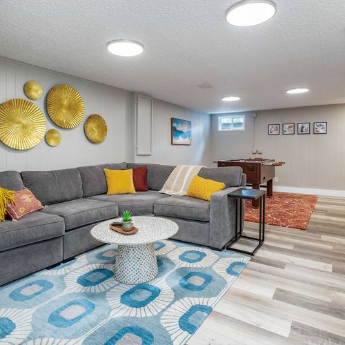 - spacious and vibrant basement lounge with a comfy sectional and bold splashes of color
- stylish gold wall art, mixed rugs, and cheerful decorative touches add personality
- perfect spot for movie marathons or lively foosball matches with friends