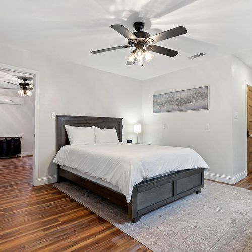 Queen bedroom w/ warm wood floors & a ceiling fan — comfortable & relaxed.