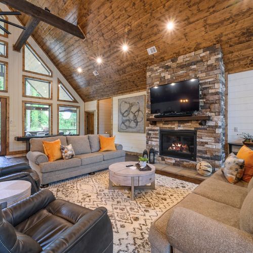 Luxury seating is placed around the stone fireplace and tv.