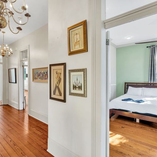 Bright hallway with charming art leading to cozy bedrooms.