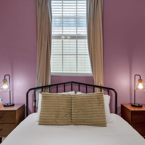 Bedroom w/ iron-frame bed & moody purple walls for a cozy, romantic feel.