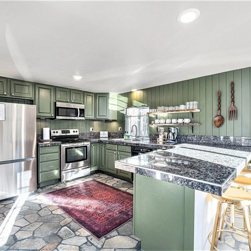 A fully stocked kitchen featuring seating at the bar area.