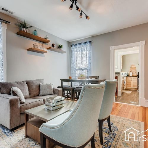 - thoughtfully designed living area with stylish floating shelves and cozy seating setup
- natural light fills the space, complemented by a rug, soft couch, and armchairs
- dining table for four creates a perfect combo of lounge and mealtime space
