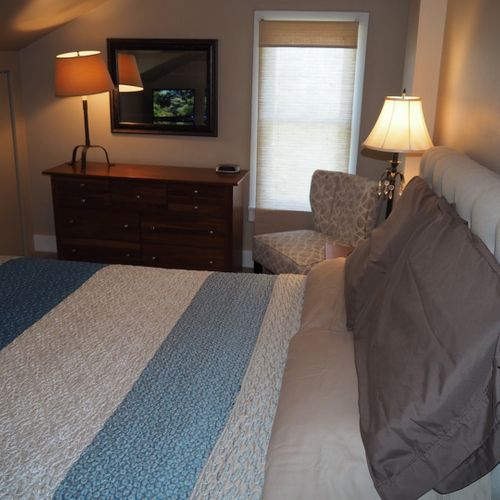 Bedroom #1:  features a queen-size bed, mirror, nightstands, lamps, dresser, chair, and television.
