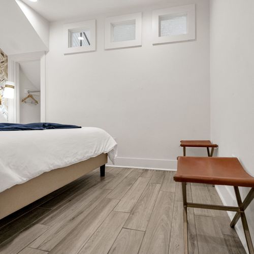 Spacious bedroom w/ warm wood tones, luxe textures & designer wallpaper.