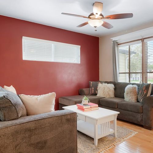 - neutral toned sofas and red accent wall create a cozy yet stylish lounge
- large windows with wooden blinds offer privacy and afternoon sun
- perfect spot to gather around the coffee table with books or board games