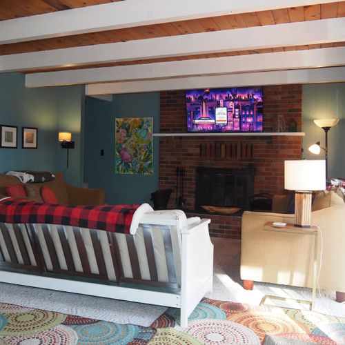 Overall:  an overview of the living room, which features lots of seating, a wood fireplace, and a large television with live-streaming via roku.
