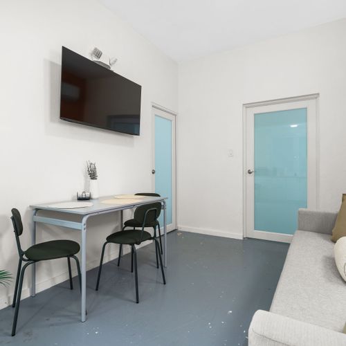 Large living area offering a plush sofa, coffee table, chairs, and flat-screen TV, perfect for entertaining friends.