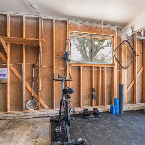 The garage is transformed into a versatile gym space, complete with essential equipment like a rower and punching bag, ideal for fitness enthusiasts to work out conveniently at home.