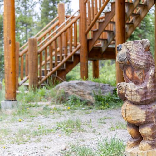 Adorable hand carved wooden bear greets guests beside the stairs, adding a playful touch to the entryway.