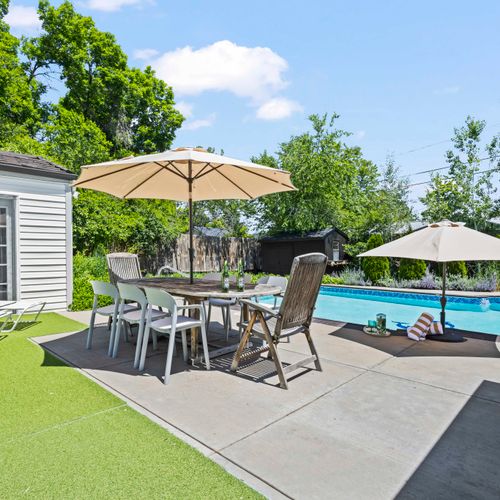 Charming patio oasis—shaded seating, refreshing pool, and sun loungers.