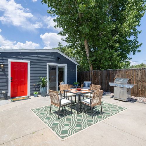 - dine alfresco in this sunny patio space featuring a modern outdoor set atop a stylish rug
- fire up the stainless bbq grill for a backyard cookout under clear blue skies
- bright red door and potted greenery add a pop of vibrant charm