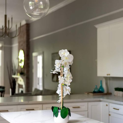 Elegant touches throughout the kitchen create a warm and inviting atmosphere. Beautiful lighting and a delicate orchid centerpiece bring a touch of sophistication, perfect for enjoying quiet mornings or lively gatherings.