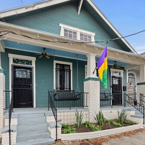 Charming teal shotgun-style home w/ a classic porch & vibrant curb appeal.
