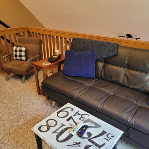 LOFT AREA (SECOND FLOOR):  Very convenient loft area with futon, wall A/C unit, coffee table, chair that unfolds into a bed, and live streaming television (via Sling).