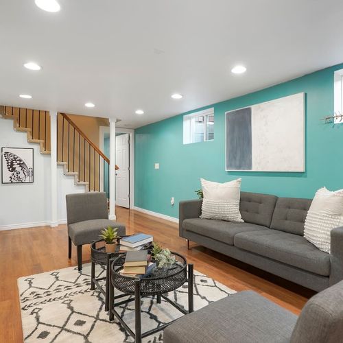 - bright basement lounge with teal feature wall and modern gray seating
- soft rug, bold art, and recessed lights create a cozy yet lively vibe
- great bonus space for reading, conversation, or winding down at night