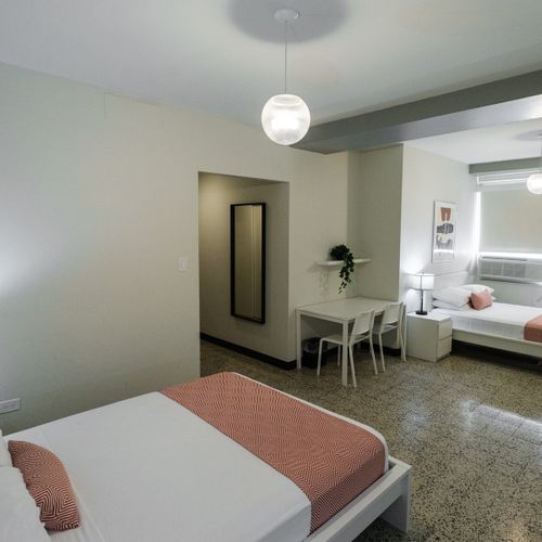 Discover a roomy and well-lit space, offering a comfortable bed and a full-length mirror, perfect for getting ready to explore or simply unwinding.