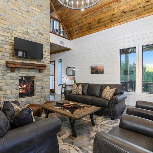 Leather couches and lounge chairs sit around the fireplace and tv!