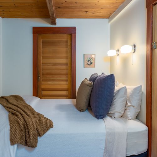 Cozy, main-floor bedroom has a queen-size bed, dresser, mirror, and luggage stand