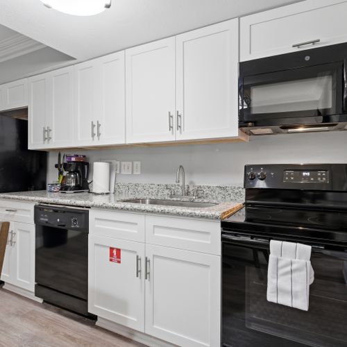 Cook with ease in a sleek kitchen w/ white cabinetry & black appliances.