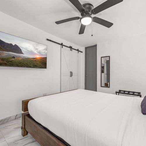 Cozy bedroom with a large TV and stylish barn doors.