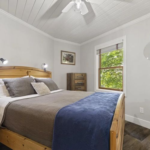 BEDROOM #1 (MAIN FLOOR):  There is conveniently a somewhat small (but gorgeous) bedroom on the main floor that features a queen-size bed, nightstand, closet, dresser, mirror, and ceiling fan.