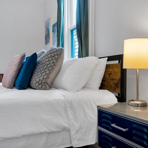 Bright, cushioned sofa w/ bold blue & mustard pillows — a cheerful spot to lounge.