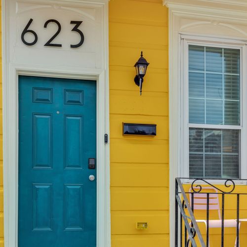 Vibrant teal front door w/ classic New Orleans yellow exterior — hard to miss & easy to love.