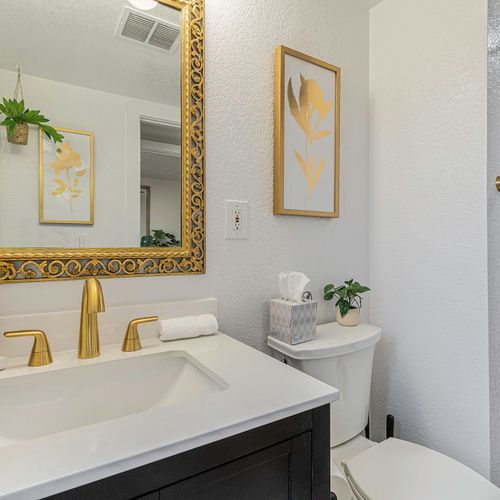 - start your day at this elegant vanity with gold fixtures, floral art, & soft lighting - richly framed mirror & custom soap set add extra flair & comfort to your routine
