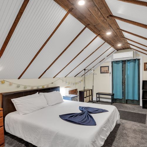 Loft-style bedroom w/ twin beds tucked under slanted ceilings — full of charm.