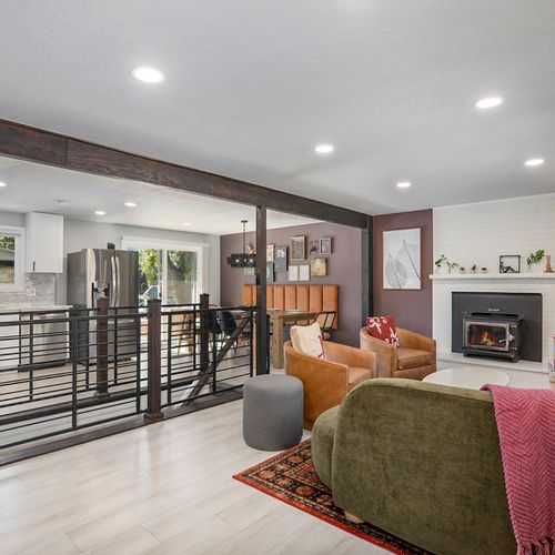 Colorful living room with open flow to dining, kitchen, and stylish staircase leading downstairs.
