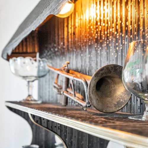 Dramatically styled bar shelf w/ vintage brass accents & moody lighting.