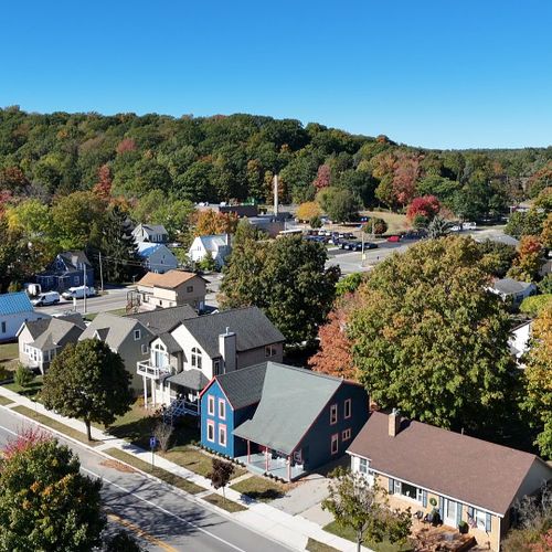 EXTERIOR:  A broad aerial view of the house and surrounding neighborhood, with Frankfort Elementary School and Tank Hill in the background