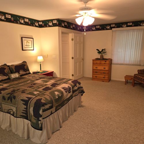 Bedroom #1:  the cabin has a large primary bedroom with a queen-size bed, desk, comfy chair, ceiling fan, dresser, and closet.