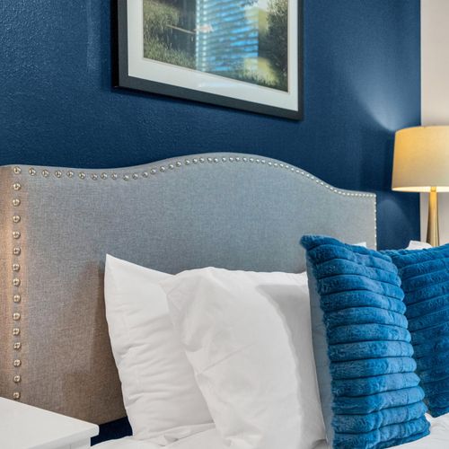 Plush bed w/ bold blue pillows & a tufted headboard for a boutique feel.