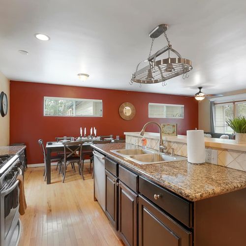 - spacious kitchen with rich granite countertops, stainless appliances, and island seating
- bold red accent wall adds character while multiple windows bring in daylight
- ideal setup for cooking, dining, and gathering in one seamless space