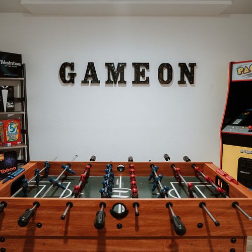 Entertainment galore in the downstairs game room, featuring a variety of board games, foosball, pac-man, a putting golf practice game, and a giant checkerboard for endless fun.