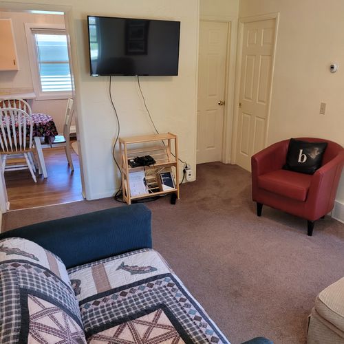 Living room:  features a loveseat, comfy chairs, live-streaming television with roku, and a ceiling fan.