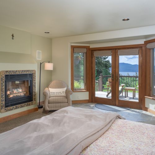 Master bedroom with a king bed, fireplace and doors opening to the decks outside.