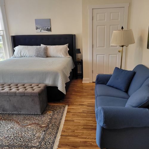 Bedroom #2 (main floor):  large main floor bedroom featuring a king-size bed, a sofa, chair, lamp, dresser, and closet.