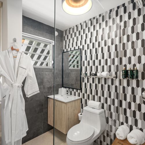 Relax and unwind in this contemporary bathroom, featuring a sleek design, beautiful tilework, and a plush robe for ultimate comfort.